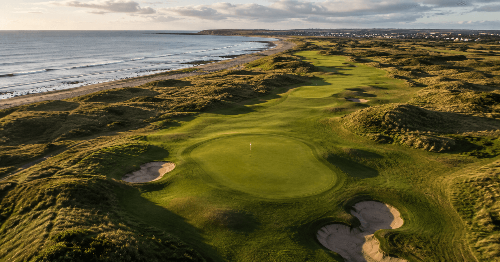 Aerial view of a links golf course with ocean backdrop, UK